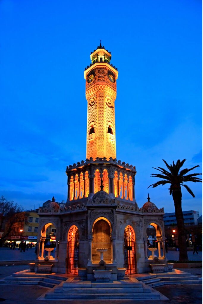Gece aydınlatılmış İzmir Saat Kulesi önünde paslanmaz çelik su deposu görseli. İzmir ve Ege bölgesine özel hijyenik ve uzun ömürlü su depolama çözümleri.